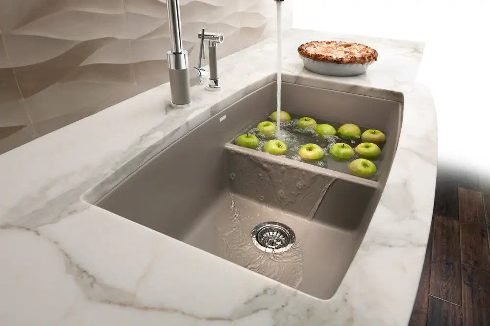 Modern kitchen sink with apples and marble countertop.