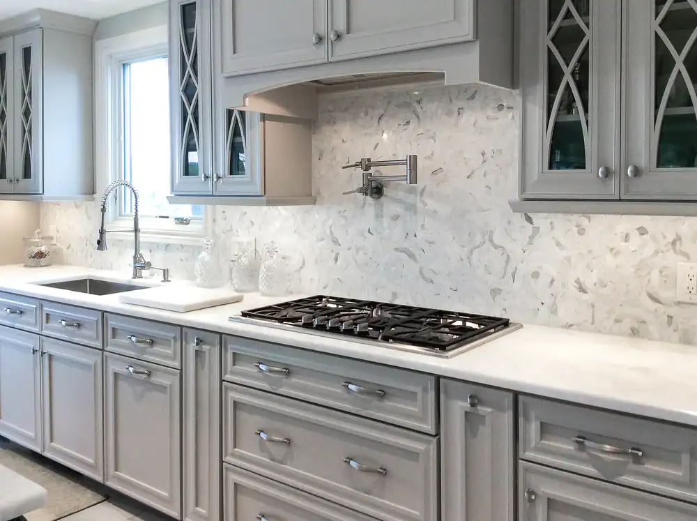 Modern kitchen with gray cabinetry and marble backsplash.