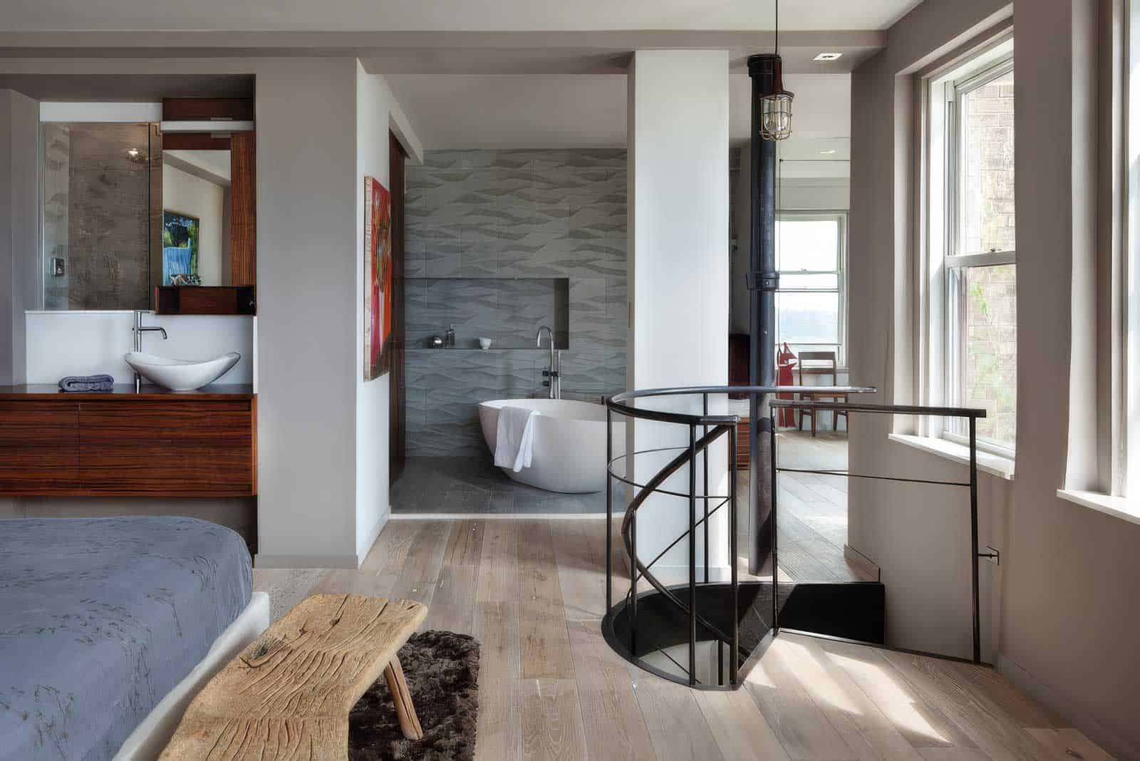 Modern interior with bathtub, spiral staircase, and large windows in a stylish home.