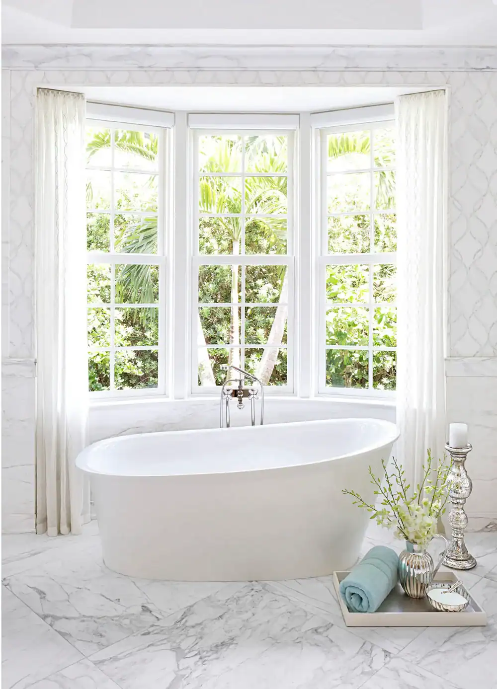 Elegant bathroom with a freestanding bathtub and large bay window with white curtains.