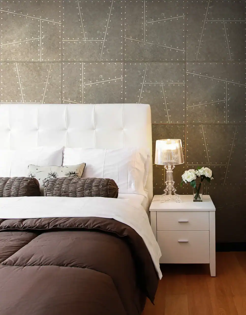 Elegant bedroom with white bed, nightstand, and decorative wall art.