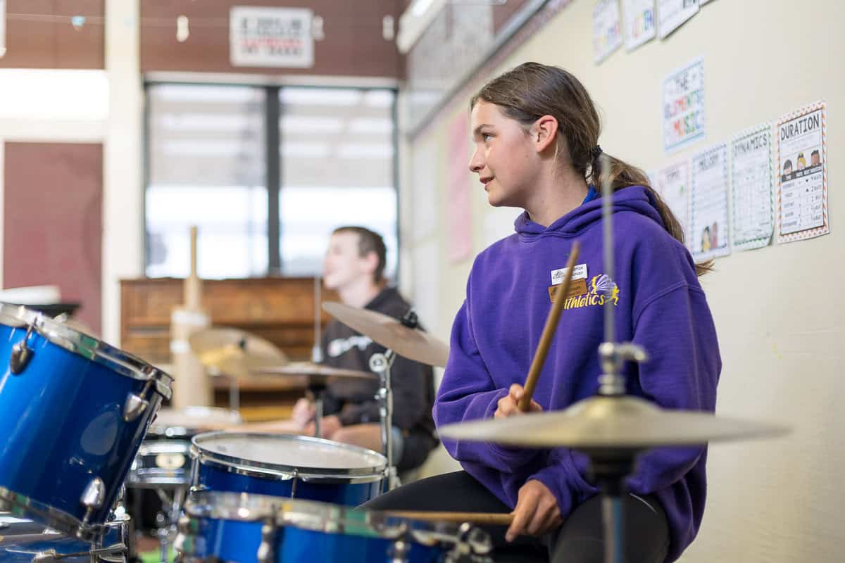 Youth girl playing drums at Bell Block School music class, promoting student arts and music programs in New Zealand.