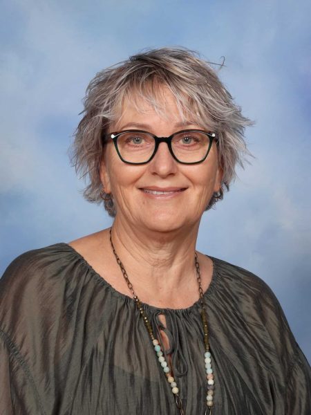 Wendy Foster, a dedicated teacher at Bell Block School, smiling outdoors with a blue sky background.