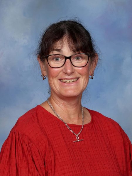 Jo Hutchinson, Bell Block School staff member, smiling in a red top with glasses.