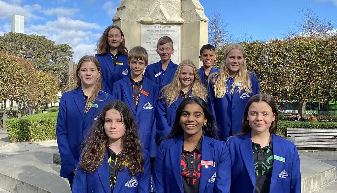 Bright students in blue uniforms standing at Bell Block School monument, showcasing vibrant school spirit and community engagement.