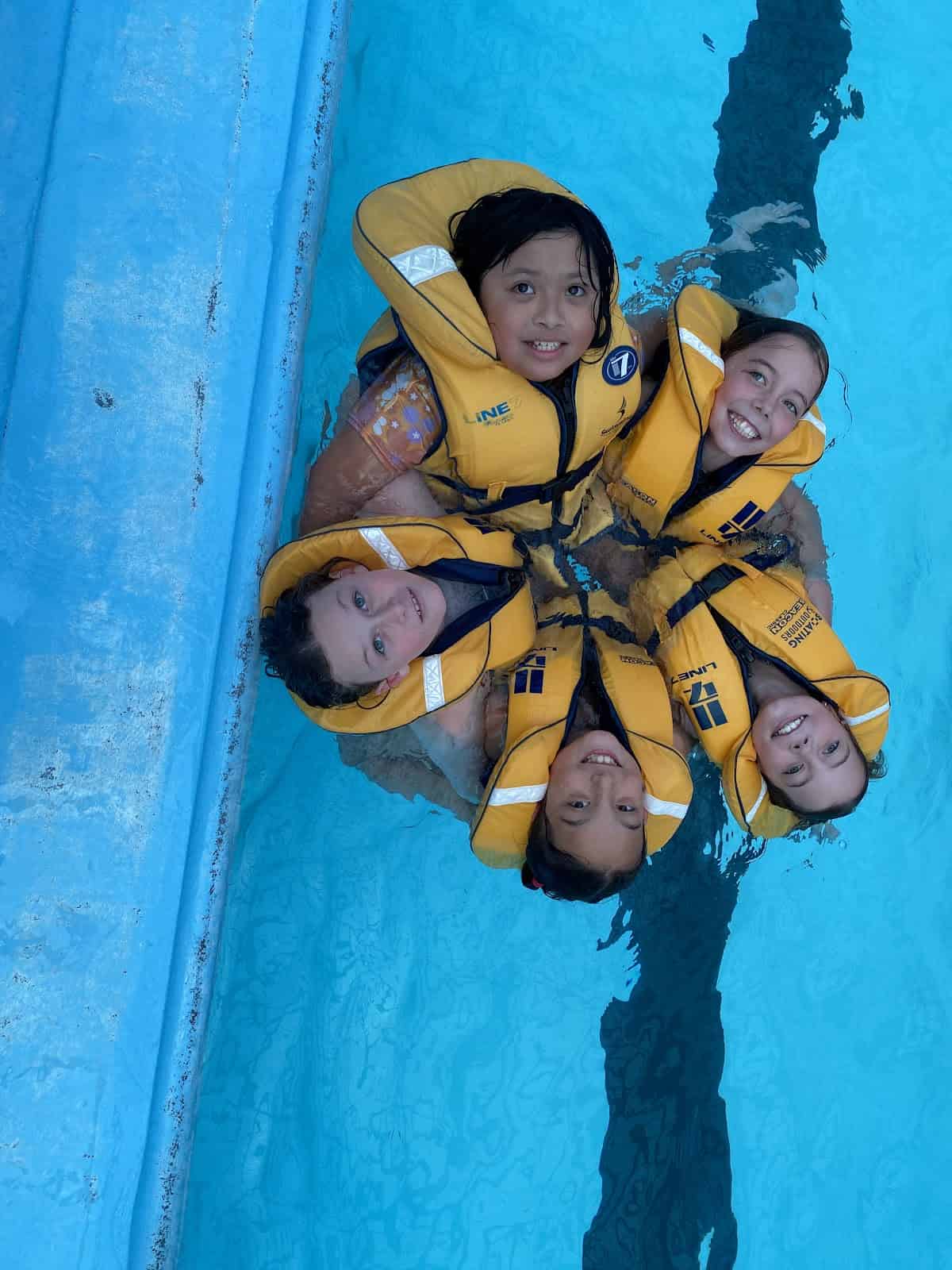 Kids swimming in a pool wearing bright yellow life jackets at Bell Block School.