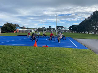 Children riding bikes on a sports court at Bell Block School in New Zealand.