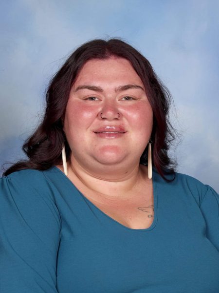 Kaia Williams smiling in a blue top against a light blue background.
