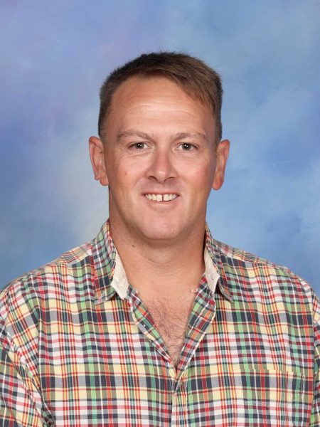 Mark Bridger, staff member at Bell Block School, smiling in front of a blue sky background.