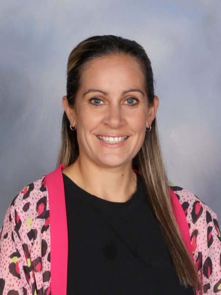 Bright smiling woman at Bell Block School staff event, colourful professional attire, quality education environment.