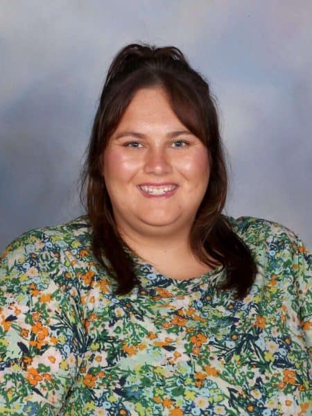 Bright smiling woman in colourful floral top, child-friendly environment, Bell Block School NZ core values.