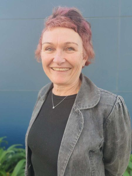 Friendly female teacher at Bell Block School in New Zealand, smiling outdoors.