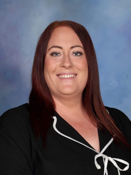 Emma Feather-Smith smiling at Bell Block School, New Zealand, with a blue background.