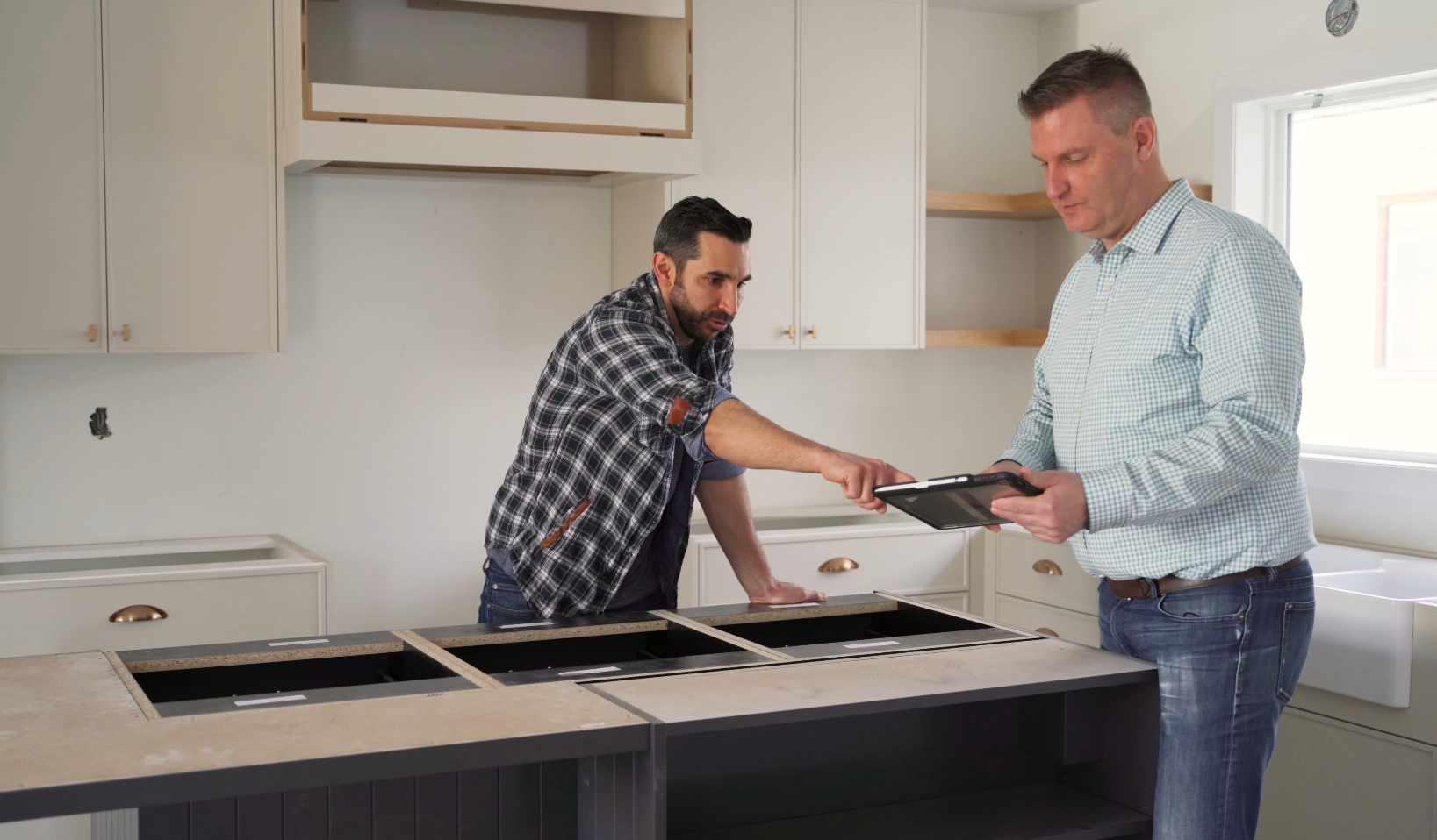 Ben Guittard (Owner) in a kitchen with a Real Estate Agent pointing to a tablet discussing renovation plans on behalf of a client.