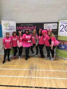 Group of women in pink costumes and tutus at charity walk event.