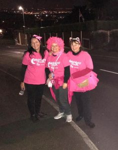 Charity volunteers in pink costumes at night, supporting Midnight Walk event.