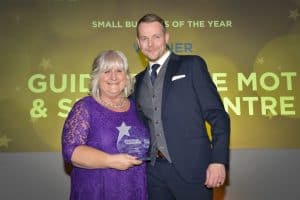 A woman and a man holding a Small Business of the Year award at Bennett Staff event.