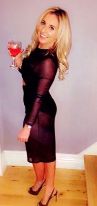 Elegant woman holding a glass of red wine, smiling confidently.