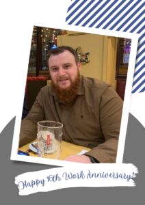 Staff member smiling at a restaurant table with a beer glass in front.