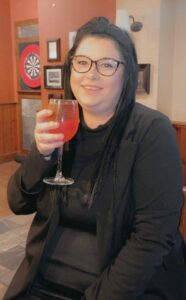 Kelsie Morton holding a drink at Bennett Staff event in a pub setting.