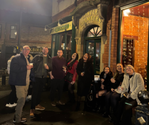 Group of friends enjoying drinks outside a traditional pub at night.