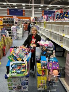 Woman shopping with toys in a supermarket aisle.