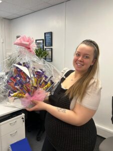 Happy woman holding a gift basket at Bennett Staff office.