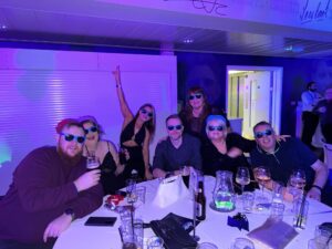 Group of people wearing sunglasses enjoying drinks at a social event.