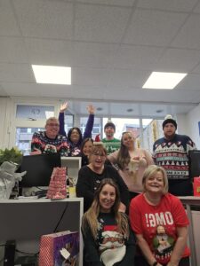 Office team wearing Christmas sweaters celebrating in festive mood.
