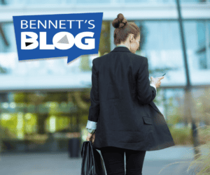Woman using smartphone outside Bennett Staff office building.