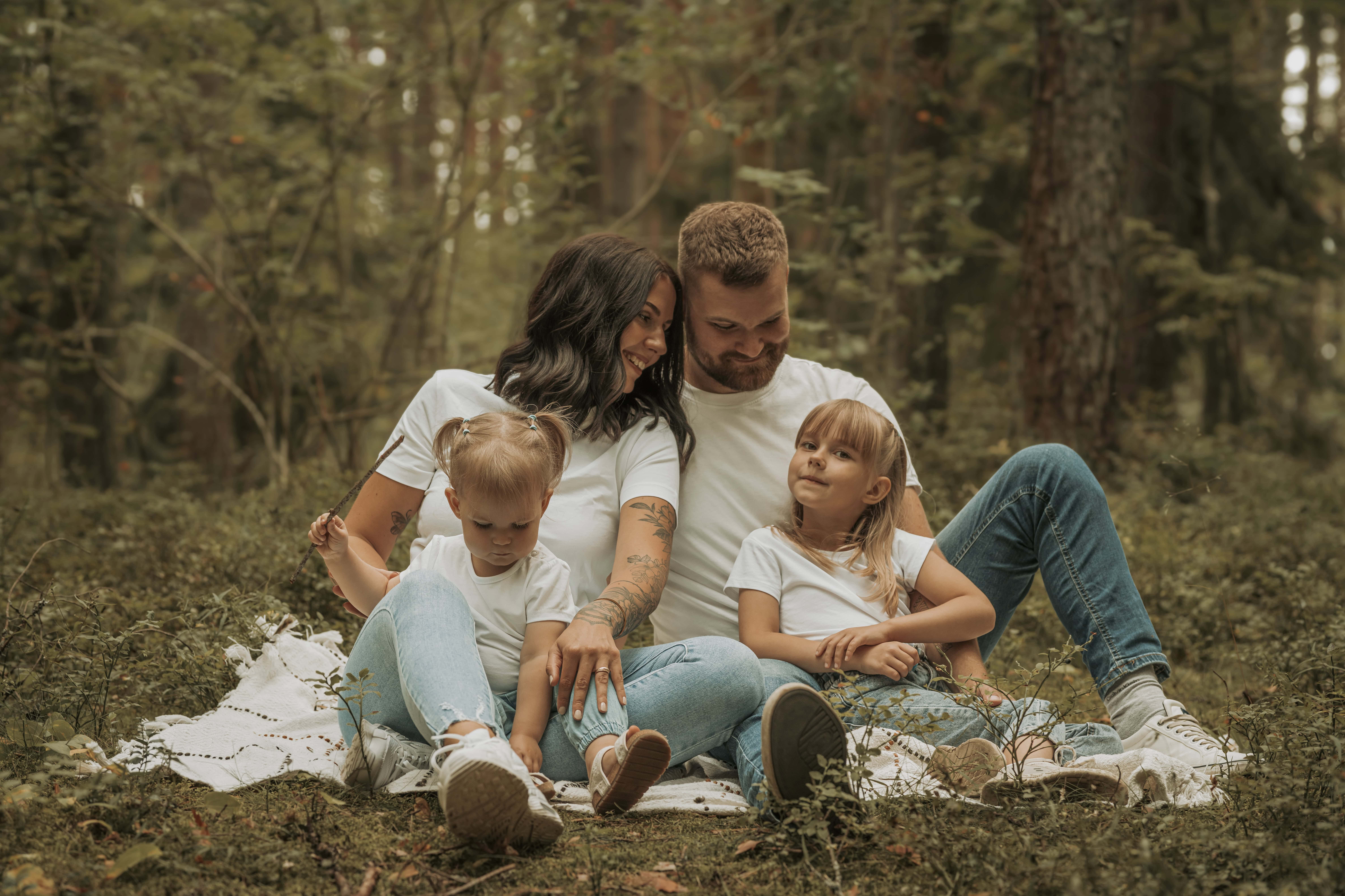 Lapsed ja täiskasvanud pere pilingul metsa taustal.