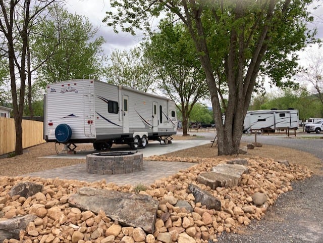 Rv park with a fire pit and trees.