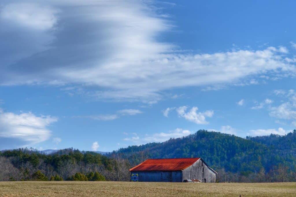 a barn in a field with mountains in the background
