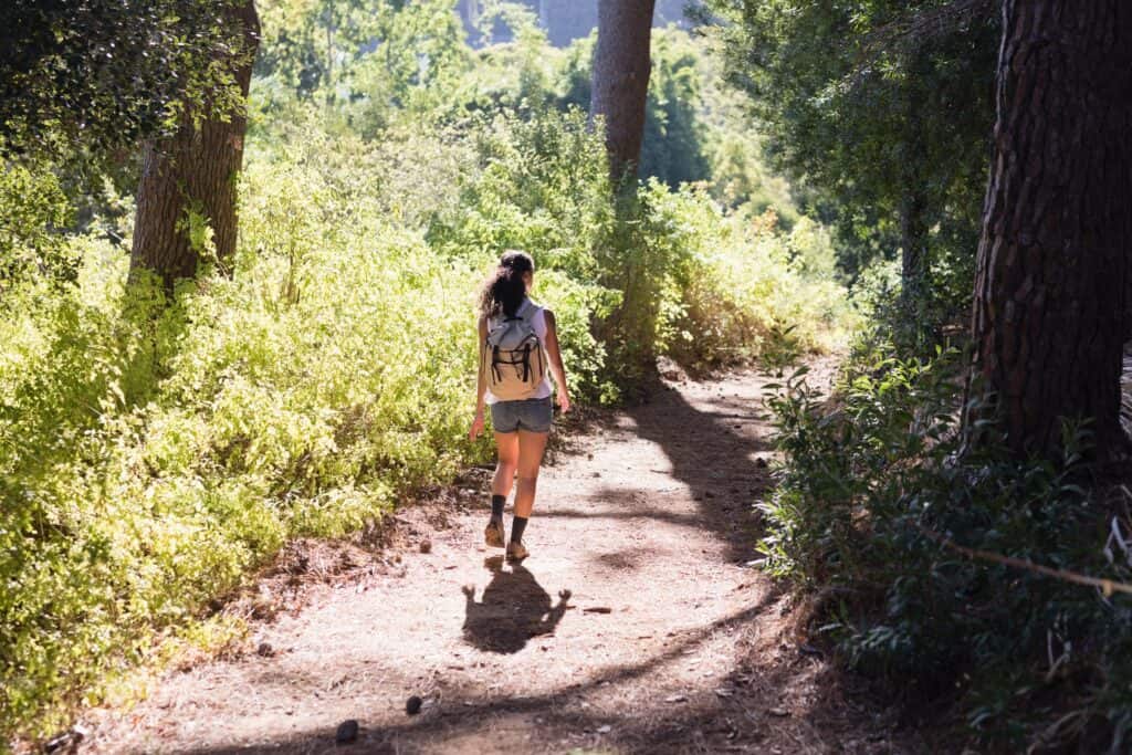A woman walking down a trail in the woods. A woman walking down a trail in the woods.