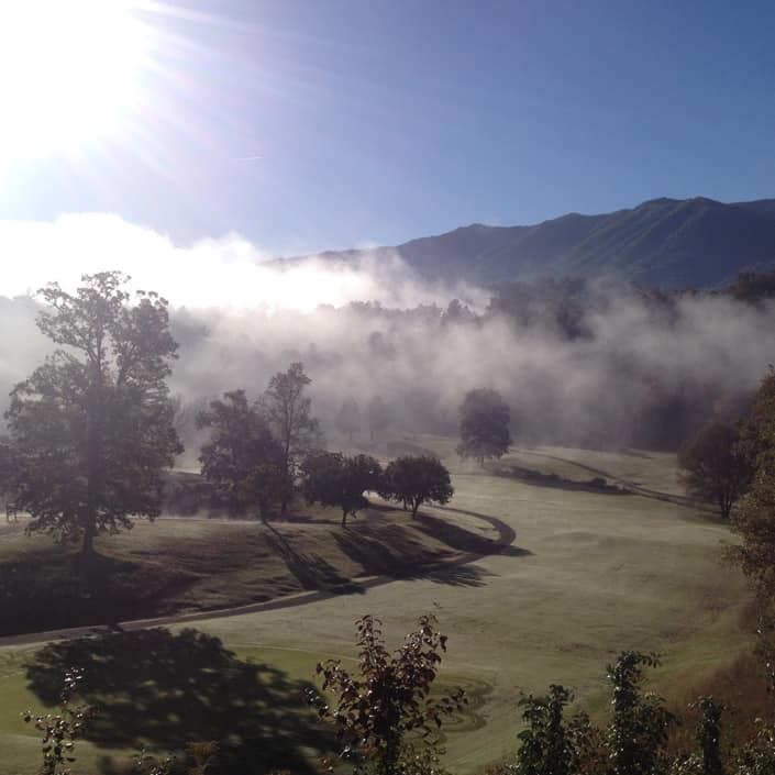 A golf course in the mist with mountains in the background. A golf course in the mist with mountains in the background.