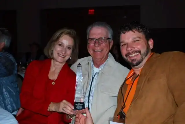 Three people posing for a picture with an award.