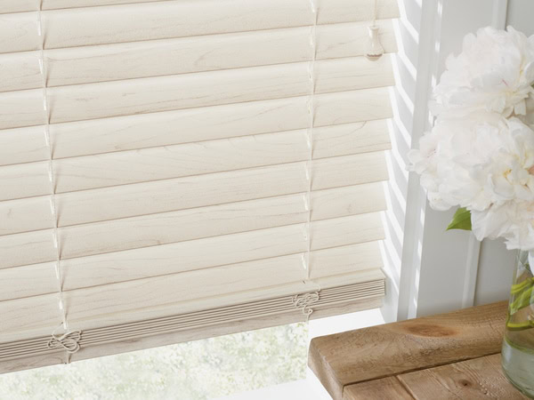 Light beige horizontal blind window covering showing sunlight filtering through, creating a bright, airy atmosphere.