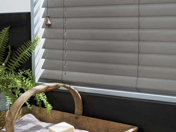Quiet grey window blinds with ladder cords in a cozy room setting.