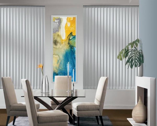 Modern dining room with vertical blinds and stylish decor including a large abstract artwork and indoor plants.