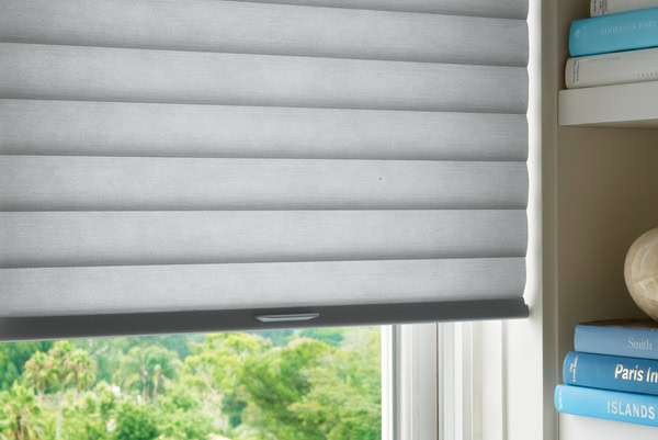 Modern grey roller blinds blocking sunlight in a bright room.