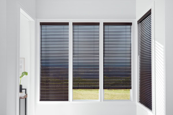 Black horizontal blinds on large window in modern home, indoor window treatment for privacy and light control.