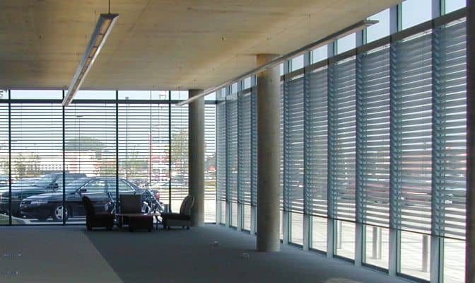 Luxurious modern office space with automated window blinds and floor-to-ceiling glass walls.