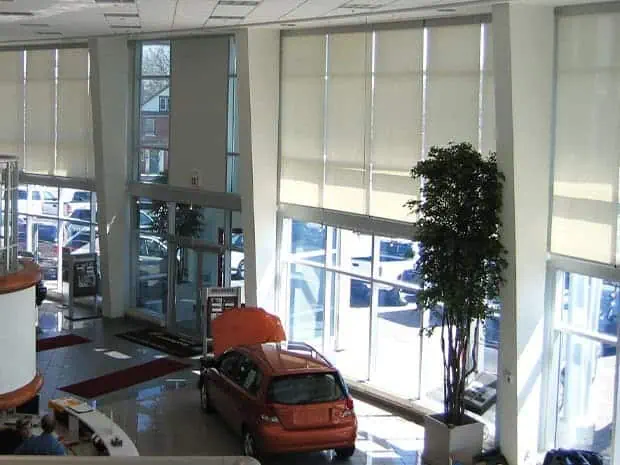 Bright indoor dealership with large glass windows and a red vehicle on display.