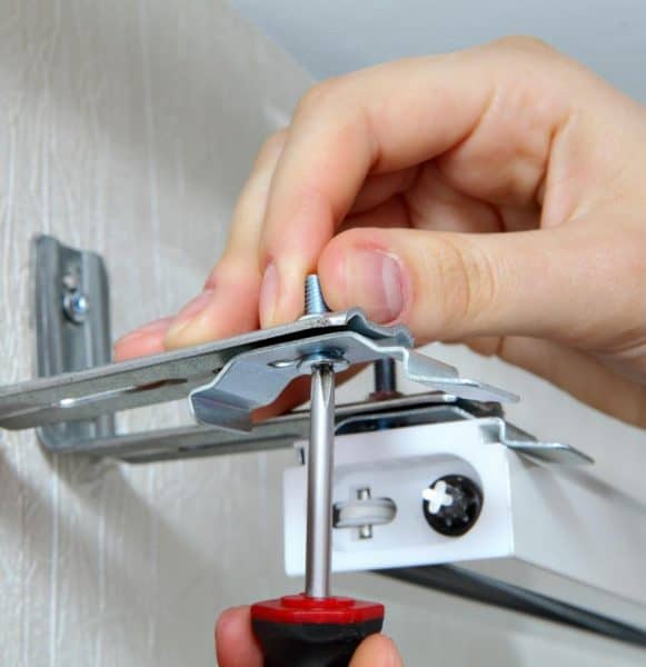 Metal blinds installation process with screwdriver for window treatment.