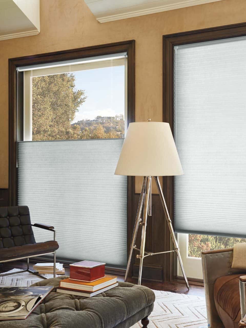 Soft grey window blinds in a modern living room, blending natural light with privacy. Stylish decor, tripod lamp, and cozy seating create inviting space.