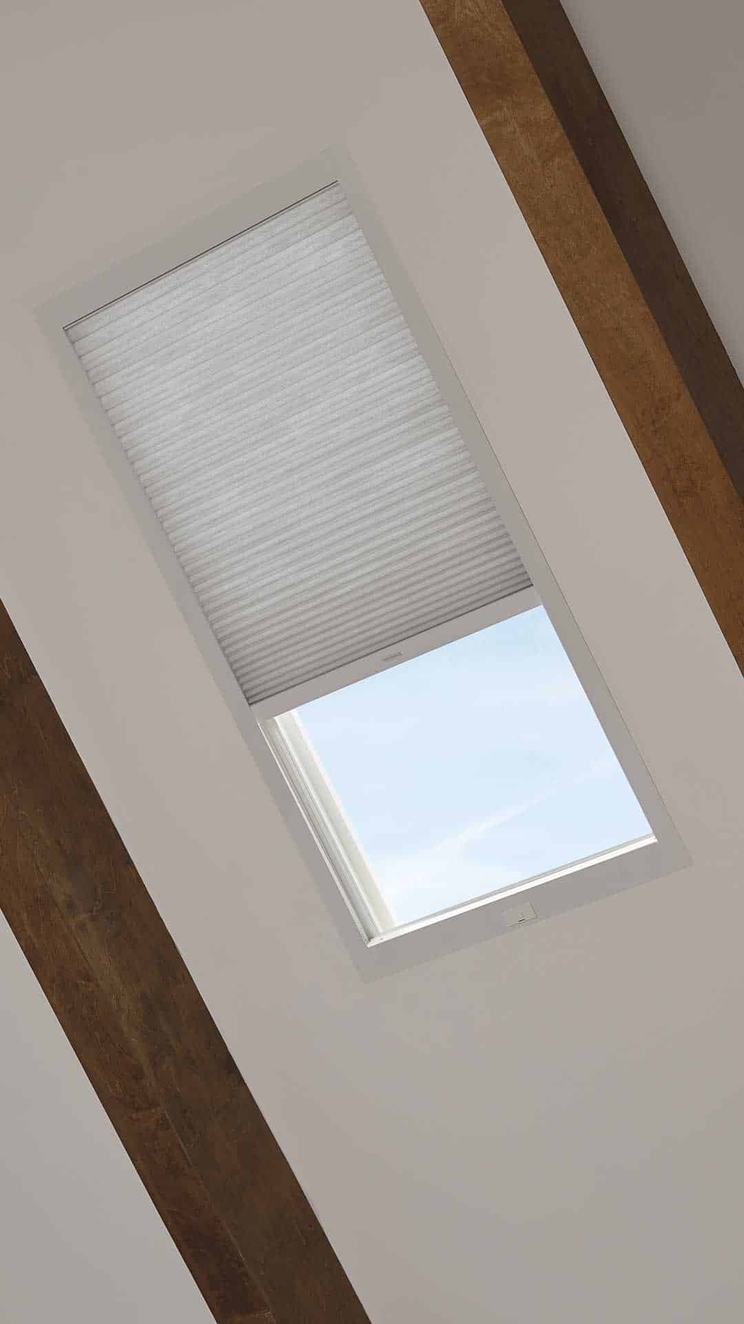 Light-filtering skylight window with automated blind for modern home interior design.
