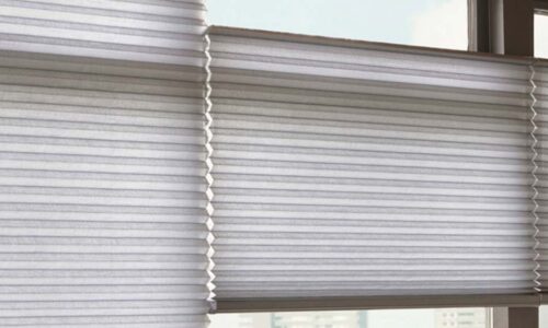 Blinds covering a large window with sunlight streaming in, creating a bright and airy atmosphere in a contemporary space.