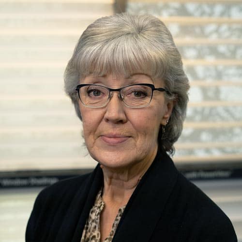 Clear image of an elderly woman with grey hair and glasses, indoors.