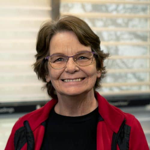 Comfortable woman with glasses smiling indoors, promoting independent living for visually impaired individuals.