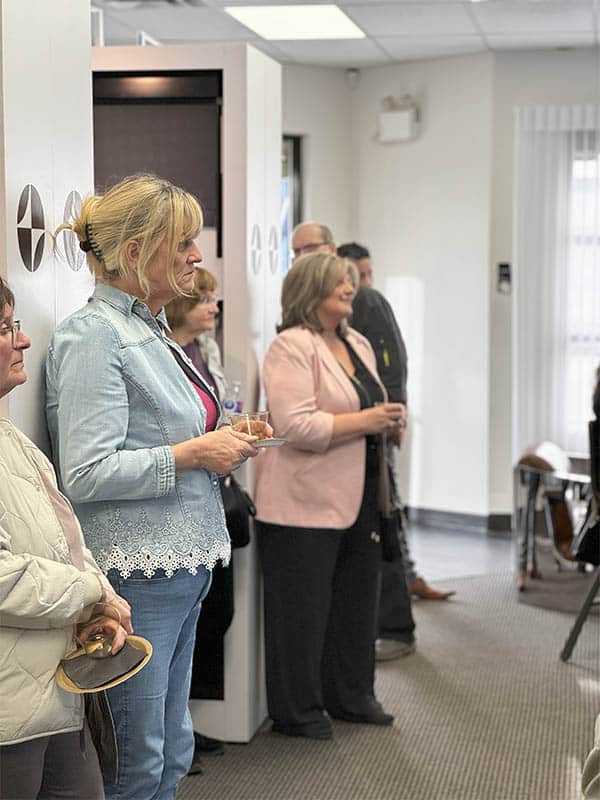 People with visual impairments attending a blind magic event in an indoor setting, holding drinks, engaging in a social gathering, showcasing inclusive entertainment.